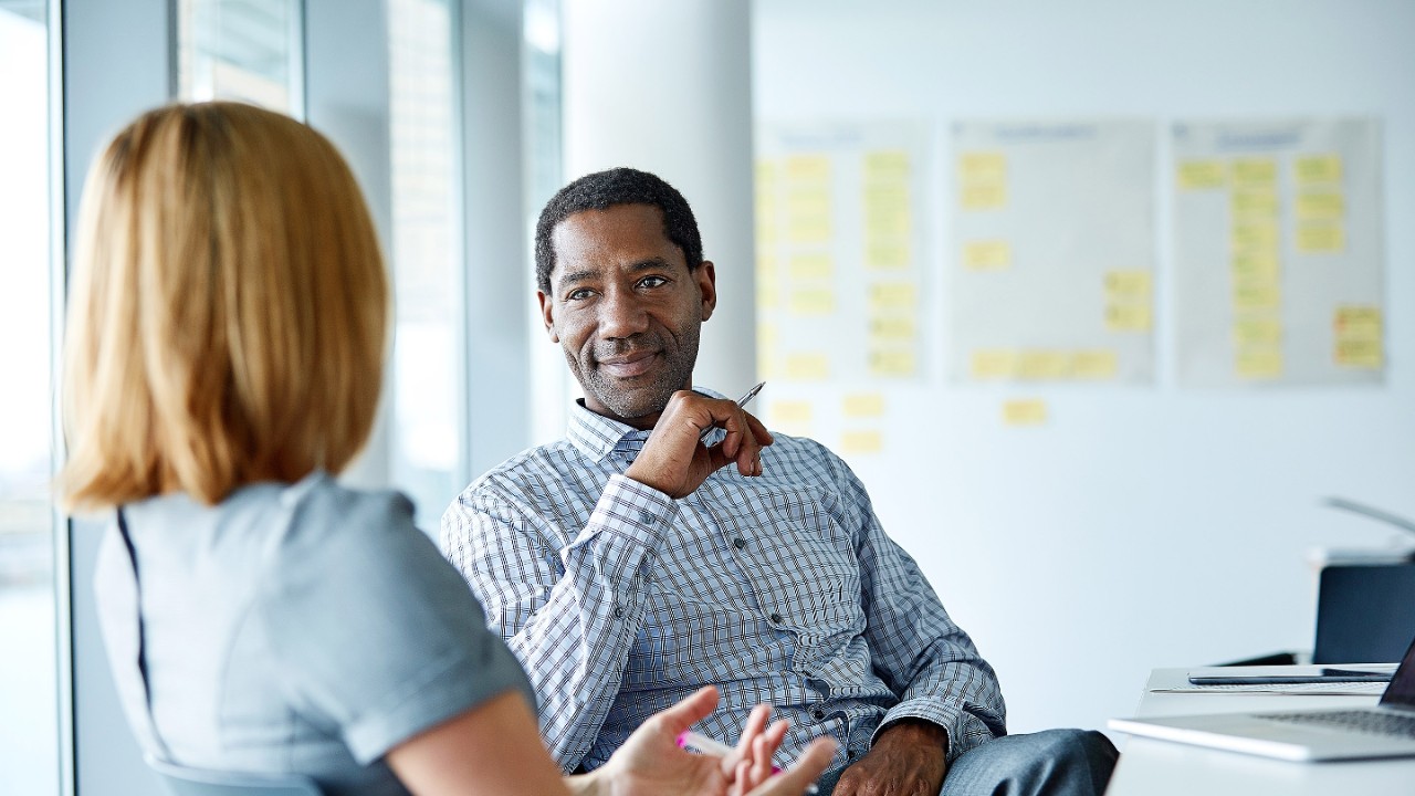 Shot of two colleagues talking together while sitting in a modern office