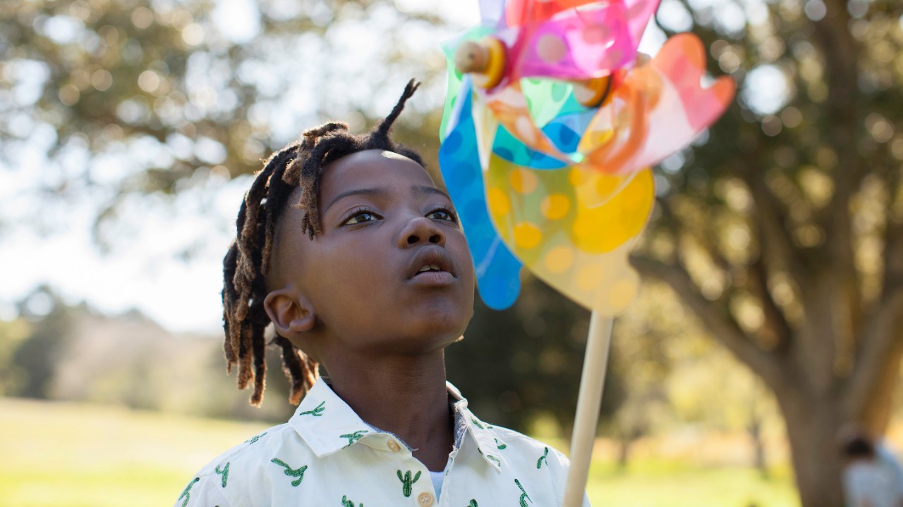 Young African boy blowing windmill in nature